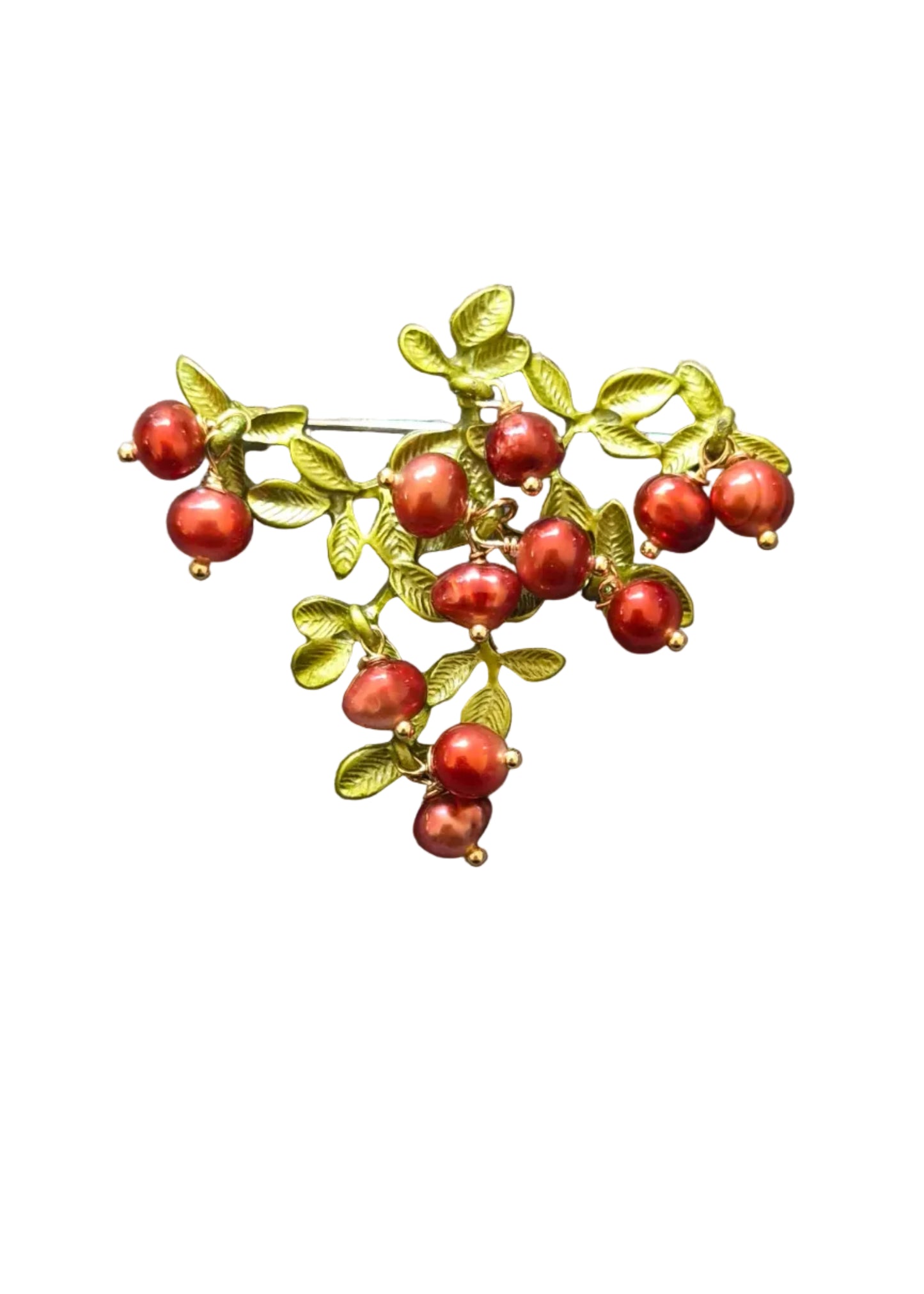 A vintage-style brooch featuring small red berries and green leaves on a gold-toned branch,.
