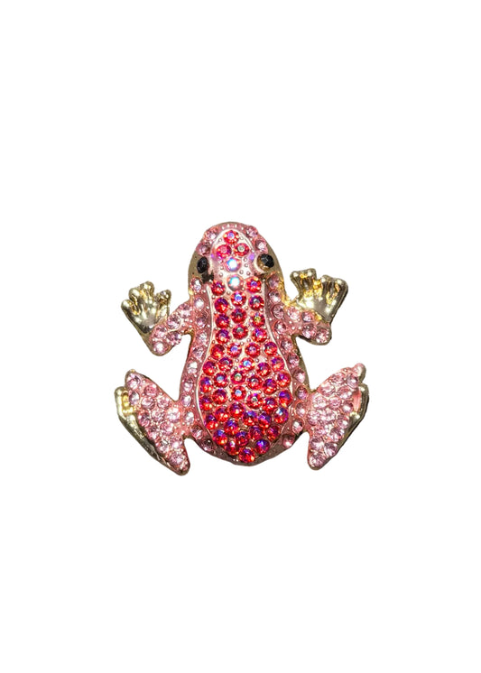 A small frog-shaped brooch or charm covered in rhinestones, with a pink body, red center, and gold-toned limbs