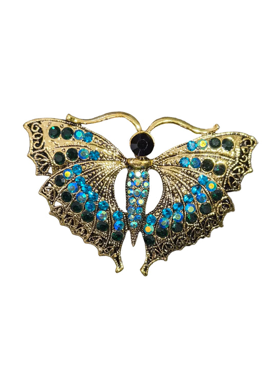A gold-toned metal moth brooch embellished with iridescent blue and green rhinestones.