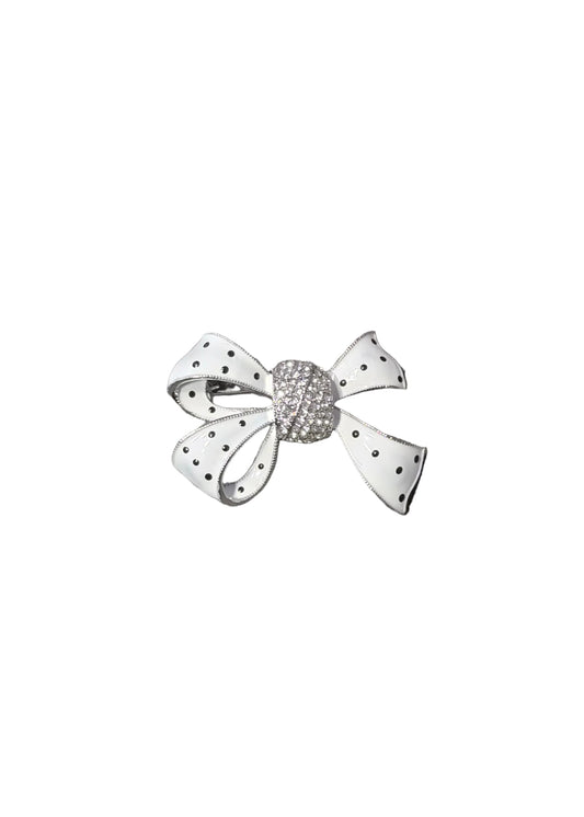 A small bow-shaped brooch with white fabric-like petals and black polka dots