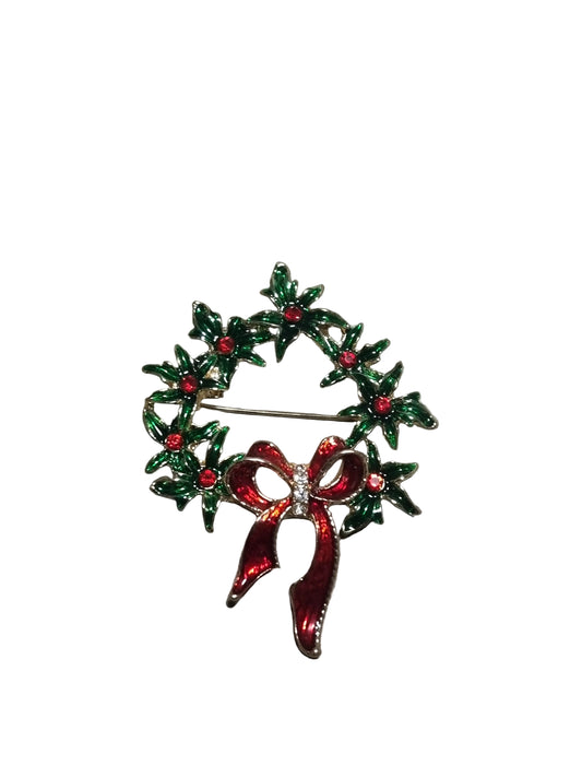 Decorative brooch with green wreath and red bow rface