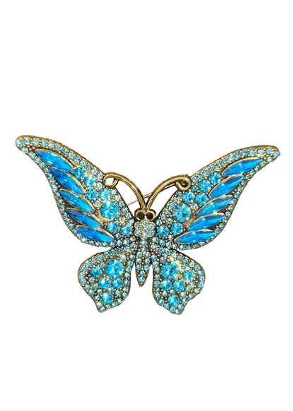 A butterfly-shaped brooch with bright blue rhinestone wings and gold-toned metal outlines