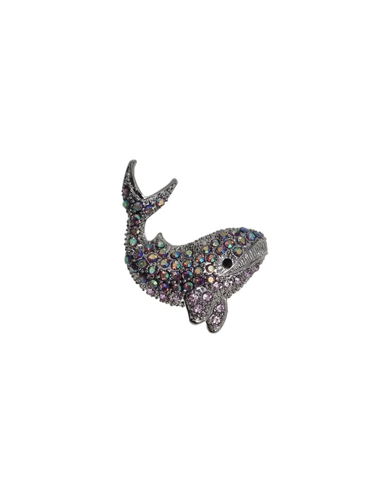 Shiny whale-shaped brooch on a white fabric background