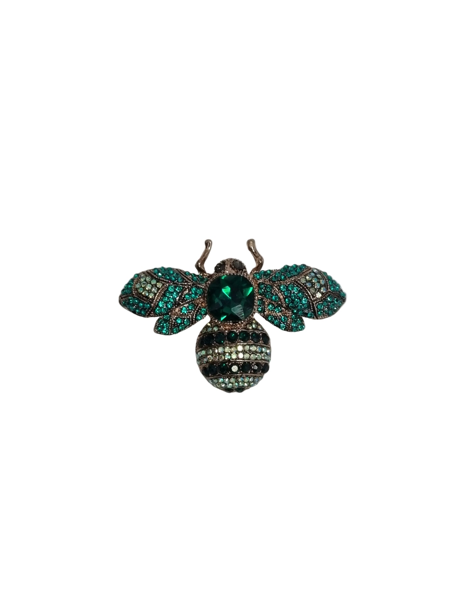 Decorative bee brooch with green and teal gemstones on a white fabric background