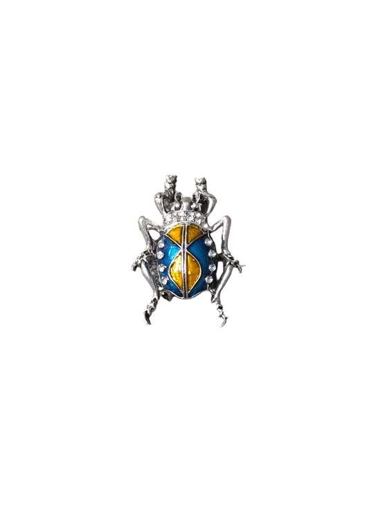 A small beetle-shaped brooch with a silver-toned body and blue, yellow, and white enamel details