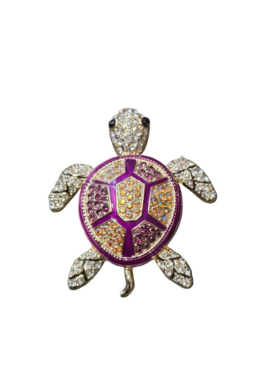 A turtle-shaped brooch or pin with a purple and gold enamel shell, set with clear rhinestones