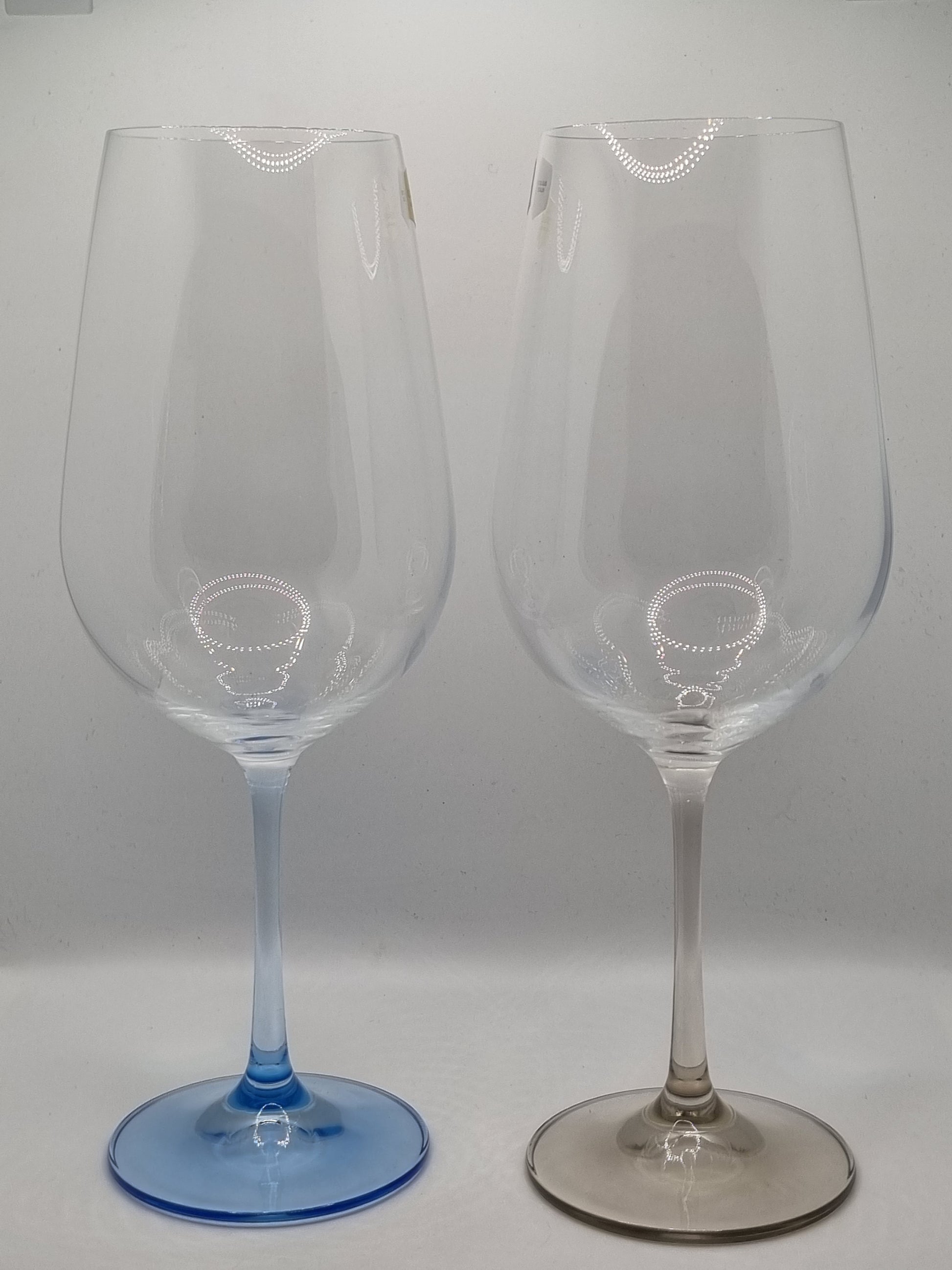 Two red wine glasses with blue and grey stems on a white background